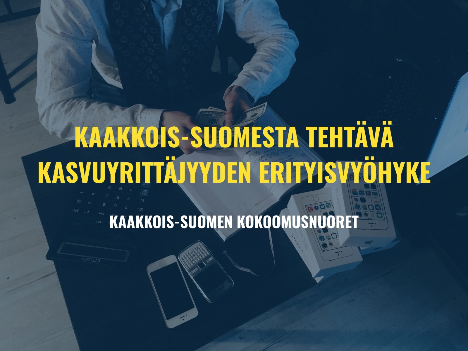 Kuvassa henkilö istuu pöydän ääressä ja laskee seteleitä. Pöydällä on muistikirja, laskin, puhelimia ja elektroniikkapakkauksia. Kuvan päällä on teksti: ”Kaakkois-Suomesta tehtävä kasvuyrittäjyyden erityisvyöhyke”. Alareunassa lukee ”Kaakkois-Suomen Kokoomusnuoret”.