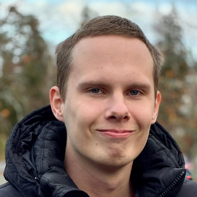 Muotokuvavalokuva Miro Vauhkosesta mustassa tikkitakissa hymyilemässä suoraan kameraan. Taustalla näkyy epäterävä syksyinen puistomainen ympäristö.